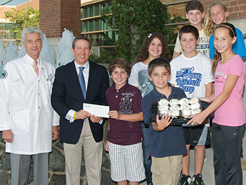 Nicholas J. Petrelli, M.D., Bank of America endowed medical director of the Helen F. Graham Cancer Center, and radiation oncologist Jon F. Strasser, M.D., receive a check from Zack Horowits and his Cupcakes4Cancer teammates Leah Harlev, Micah Harlev, Clay Horowitz, Justin Horowitz, Sdney Flambaum and Haley Flambaum.