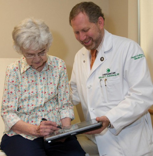 Doctor using computer pain self-assessment tool with patient.
