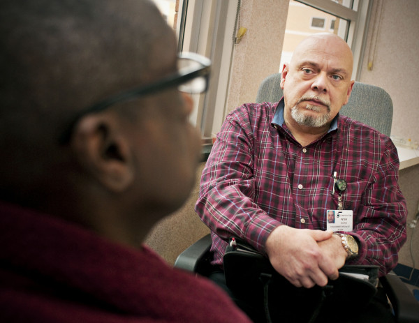 Peter Booras, engagement specialist , counsels a patient in Project Engage. The program has connected more than 1,000 hospital patients with resources to help them overcome substance abuse problems.