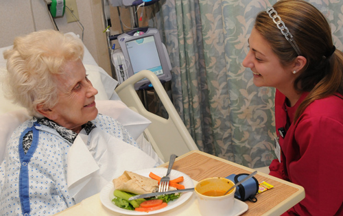 Volunteer Jillian Buck helps patient Grace Miliewski enjoy lunch at Christiana Hospital’s 6A (ACE) unit.