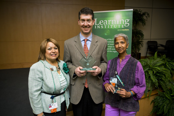 Rosa Colon-Kolacko, Ph.D., MBA, senior vice president, System Learning/Learning Institute, and chief diversity officer, presents Allen Friedland, M.D., FACP, FAAP, and Seema Sonnad, Ph.D., with Distinguished Mentor awards.