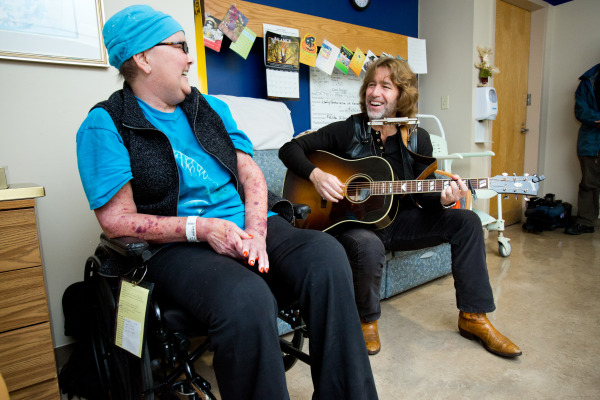John Flynn and Janice Ruge share a laugh during his acoustic performance in her hospital room at the Center for Rehabilitation.