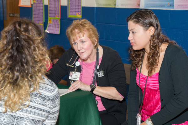 Aided by a medical interpreter, Nora Katurakes, RN, MSN, OCN, Christiana Care’s manager of Community Health Outreach & Education, talks to a Latina Conference attendee about screening results.