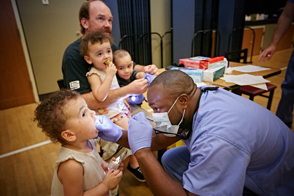 Dental resident Pat Whilby, D.D.S., examines Adriana Lovaas' teeth at the Sunday Breakfast Mission’s Back-to-School Event.