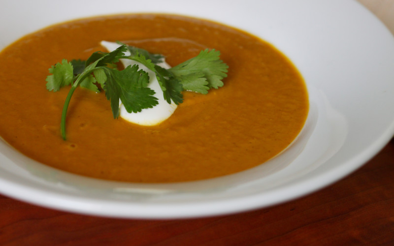 Pumpkin coconut curry soup garnished with greek yogurt and a sprig of cilantro.