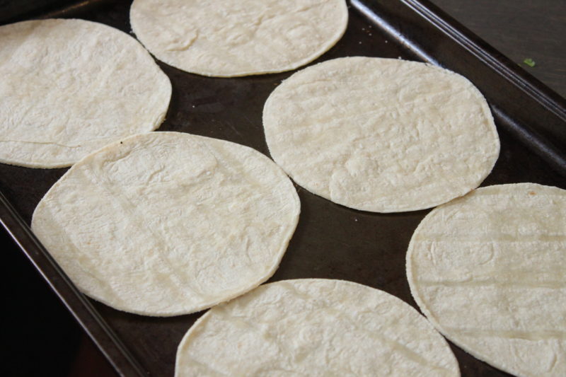 Briefly baking the tortillas before filling makes them pliable enough to roll without cracking and sturdy enough to bake in the sauce without disintegrating.